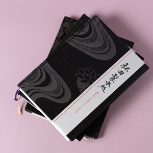 May include: Two black notebooks with a white cover and Japanese text that reads "Body and Soul". The notebooks have a black and gray patterned design.