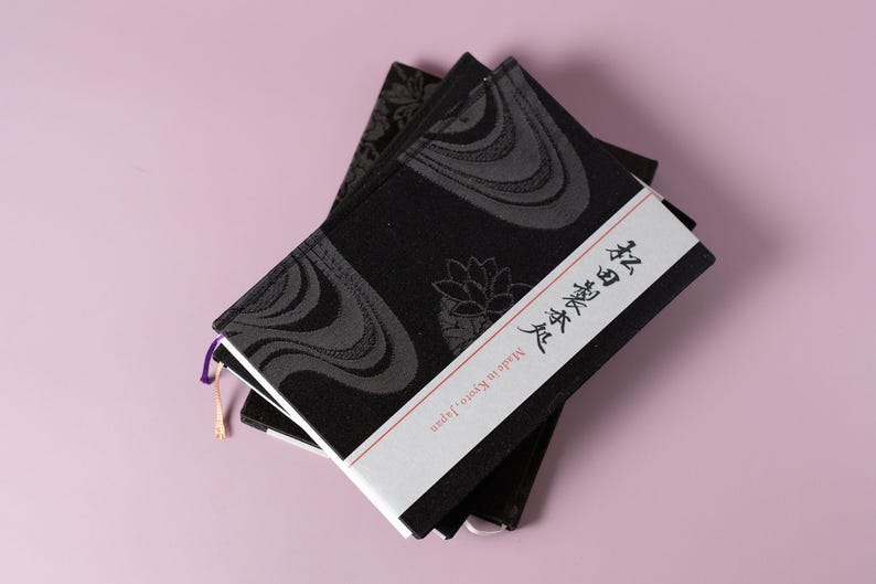 May include: Two black notebooks with a white cover and Japanese text that reads "Body and Soul". The notebooks have a black and gray patterned design.