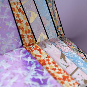 May include: A collection of colorful patterned Japanese washi tape rolls. The tape features designs of flowers, birds, and geometric patterns. The rolls are labeled with the text "Bring a little joy to your life!"