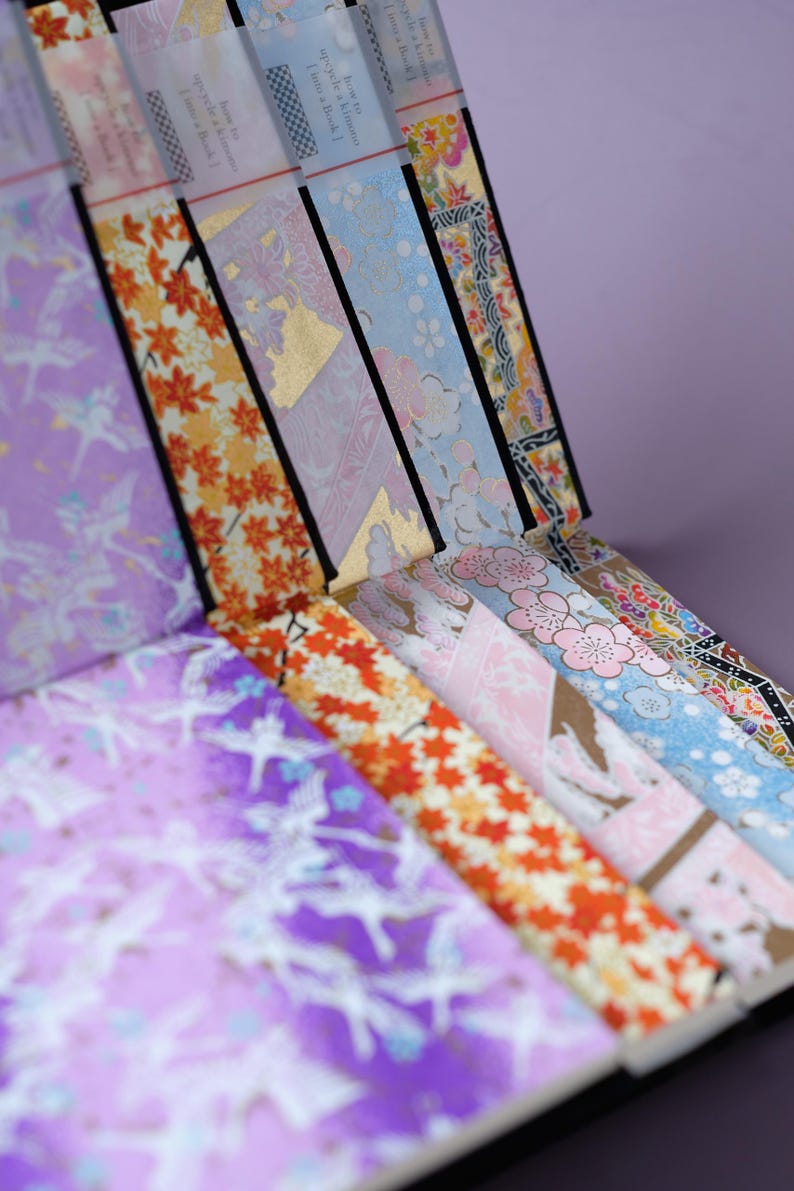 May include: A collection of colorful patterned Japanese washi tape rolls. The tape features designs of flowers, birds, and geometric patterns. The rolls are labeled with the text "Bring a little joy to your life!"