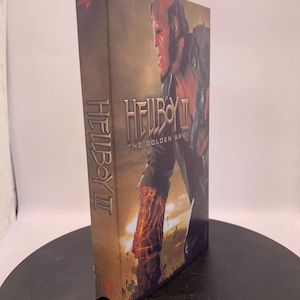 May include: A Hellboy II: The Golden Army DVD case. The cover features a red-skinned character with horns and the film's title. The Universal logo is visible on the top left corner. The case has a brown and orange color scheme.