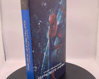 Puede incluir: Caja Blu-ray de la película "The Amazing Spider-Man". La portada presenta a Spider-Man con un traje rojo y azul sobre un fondo de paisaje urbano. El lomo es azul con el título de la película en blanco. El logotipo de Columbia Pictures es visible.