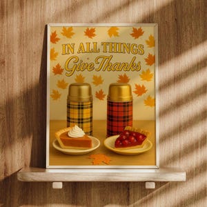 Könnte beinhalten: Ein gerahmter Druck mit dem Text "IN ALL THINGS Give Thanks" und Herbstblatt-Illustrationen. Zwei karierte Thermoskannen und Tortenstücke befinden sich darunter. Das Bild befindet sich auf einem Holzregal mit Holzgrund.