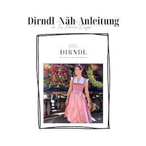 May include: A pink dirndl with white trim and a white blouse. The dirndl is being worn by a woman standing in front of a flower arrangement. The text "DIRNDL" is printed on the cover of a book.
