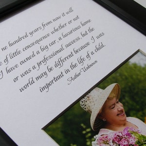 May include: A framed print with a black and white photo of two people, an older woman and a younger girl, smiling at each other. The print includes a quote: "One hundred years from now it will be of little consequence whether or not I have owned a big car, a luxurious home or was a professional success, but the world may be different because I was important in the life of a child." - Author Unknown
