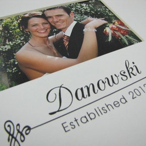 May include: A white photo frame with a black border and a photo of a couple. The frame has the text "Danowski Established 2012" printed on it.