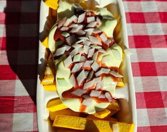 May include: A rectangular white tray filled with golden yellow french fries topped with a generous layer of creamy pale yellow mayonnaise, a drizzle of reddish-brown curry ketchup, and a scattering of finely diced white onion pieces.
