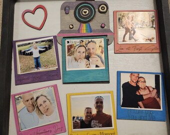 May include: A framed collage of photos with a wooden camera cutout in the center. The photos are in different colored frames and have captions like "Love at First Sight", "Happy Valentine's Day", "Picture this You and Me", and "Capture Every Moment".
