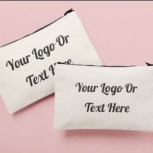 Może przedstawiać: Dwie białe płócienne kosmetyczki z czarnym wykończeniem. Kosmetyczki mają nadrukowany tekst "Your Logo Or Text Here".