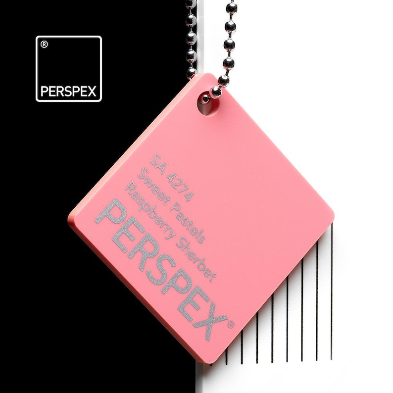 May include: A pink Perspex color swatch, square-shaped with rounded corners, hangs from a silver ball chain. The swatch features the text "PERS PEX" and the color name "Raspberry Sherbet". The background is split black and white.