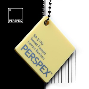 May include: A square, pale yellow Perspex color swatch, suspended by a silver chain. The swatch has the text "SA 2170 Sweet Pastels Lemon Bonbon PERSPE&shy;X" printed in blue. The background is black and white.