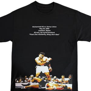 May include: Black t-shirt with a white print of a boxing match between Muhammad Ali and Sonny Liston. The text reads "Muhammed Ali vs. Sonny Liston, May 25, 1965, Lewiston, Maine, All won, 1st round knockout, "Float Like A Butterfly, Sting Like A Bee."