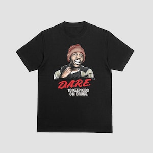 Może przedstawiać: Czarny t-shirt z grafiką mężczyzny w brązowej czapce. Grafika zawiera napis "D.A.R.E. TO KEEP KIDS ON DRUGS" w kolorze czerwonym i białym. Koszulka ma okrągły dekolt i krótkie rękawy.