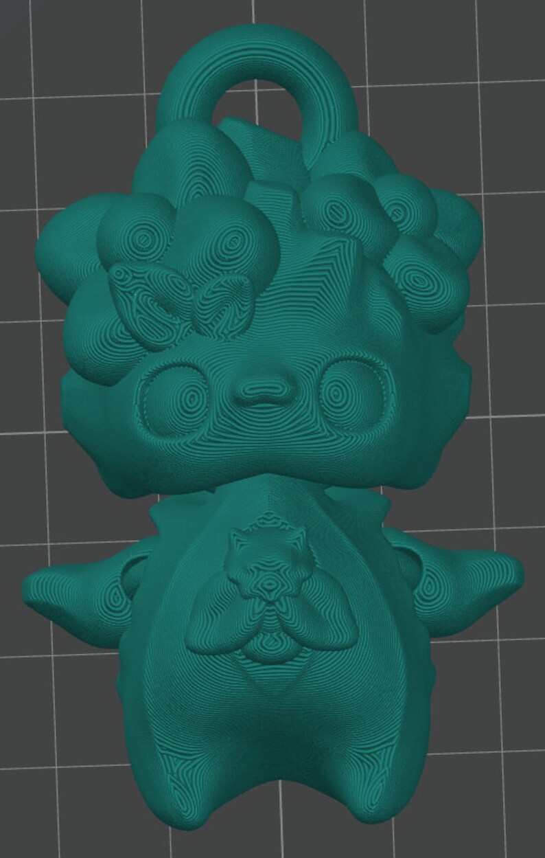 Puede incluir: Figura teal impresa en 3D de una criatura estilizada con ojos grandes, una parte superior en bucle y una superficie texturizada detallada. El dise&ntilde;o incluye una forma de lazo y un emblema central en el pecho.