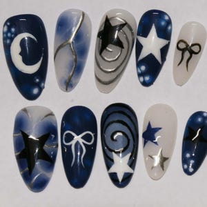 May include: Set of ten blue and white nail tips with various designs including stars, moons, and bows.