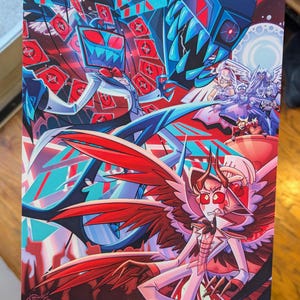 May include: A striking print with a dynamic composition of stylized characters. The artwork features figures in red, blue, and white, set against a geometric background. The print has a signature in the bottom left corner.