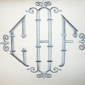 May include: A silver embroidered monogram with the letters "GAF" in a diamond shape with decorative flourishes.