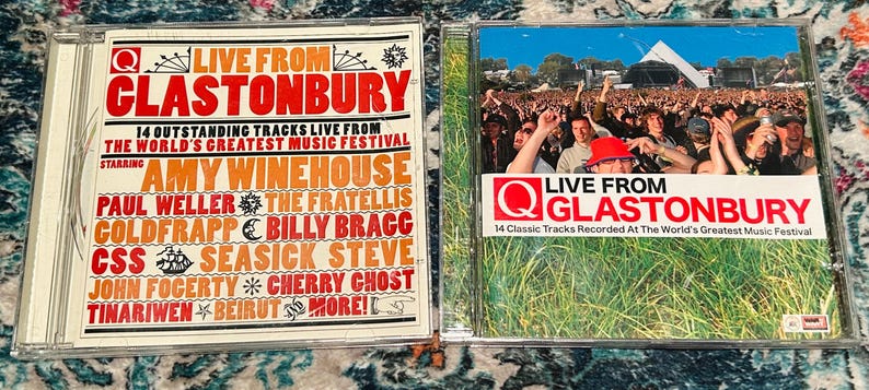 Może przedstawiać: Dwa krążki CD z muzyką "Live From Glastonbury". Jedna obudowa CD ma czerwono-biały design z nazwiskami artyst&oacute;w, takich jak Amy Winehouse. Druga obudowa CD ma zdjęcie tłumu na festiwalu muzycznym z tekstem "Live From Glastonbury".
