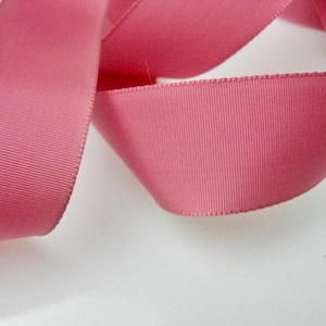 Op de afbeelding: Een close-up van een roze satijnen lint, met de textuur en glans van de stof.