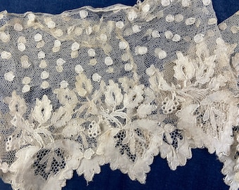 May include: Close-up of delicate off-white lace fabric. The lace features a floral pattern along the scalloped edge, with a dotted design in the upper portion. The intricate details and open weave create a vintage aesthetic, suitable for various craft projects.