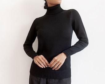 May include: A black turtleneck sweater with long sleeves. The sweater is made of a soft, comfortable material and has a relaxed fit.