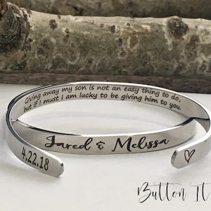 May include: Silver bangle bracelet with an engraved message: "Giving away my son is not an easy thing to do, but if I must I am lucky to be giving him to you." The bracelet also has the names "Jared & Melissa" and the date "4.22.18" engraved on it.