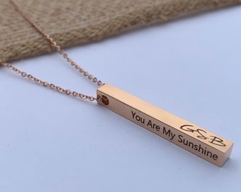 May include: Rose gold bar necklace with the inscription "You Are My Sunshine" and the initials "GSB".