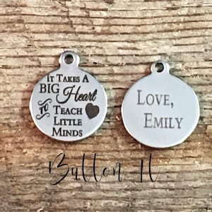 May include: Two silver-colored round charms. One charm reads "It Takes A Big Heart To Teach Little Minds" with a heart graphic. The other charm says "Love, Emily". Both charms have a small hole at the top.