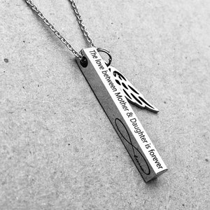May include: Silver necklace with a vertical bar pendant that reads "The love between Mother & Daughter is forever" with an infinity symbol and an angel wing charm.