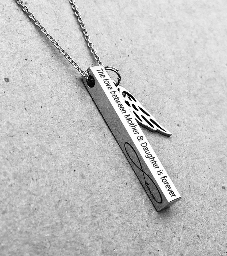 May include: Silver necklace with a vertical bar pendant that reads "The love between Mother & Daughter is forever" with an infinity symbol and an angel wing charm.