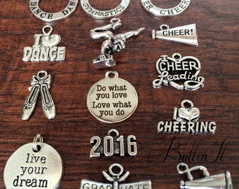May include: A collection of silver charm pendants with various themes, including dance, cheerleading, gymnastics, and graduation. The charms feature words like "I Love Dance", "Cheer Leading", "Do What You Love", "Live Your Dream", and "Graduate".