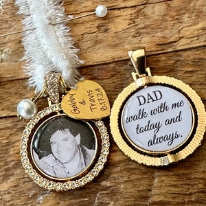 May include: Two gold tone memorial charms. One charm features a photo of a man in a round frame with rhinestones around the edge. The other charm is round with the text "DAD walk with me today and always."