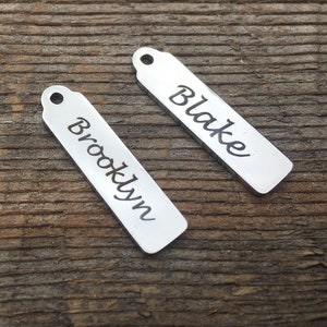 May include: Two silver metal tags with the names "Blake" and "Brooklyn" engraved on them.
