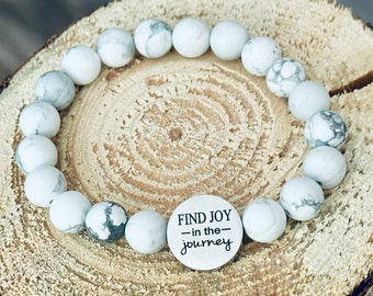 May include: White howlite beaded bracelet with a silver charm that reads "FIND JOY - in the - journey".