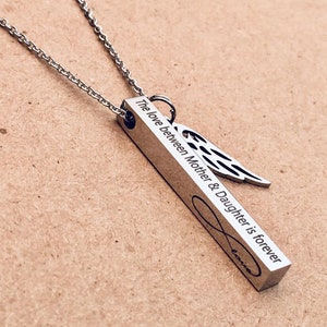 May include: A silver necklace with a bar pendant that reads "The love between Mother & Daughter is forever" with an infinity symbol and an angel wing charm.