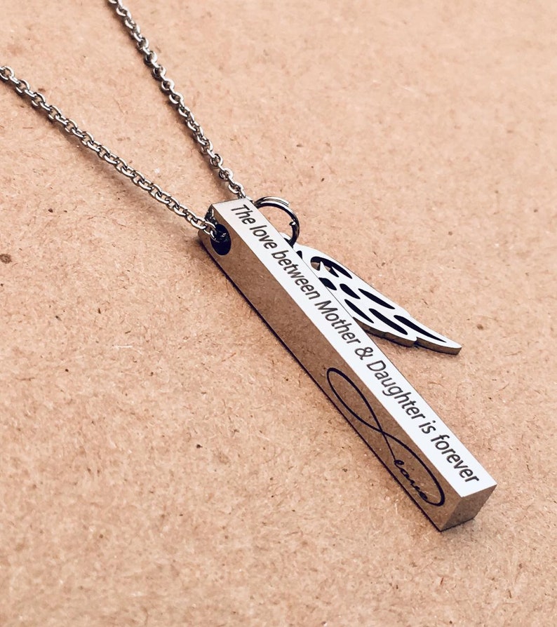 May include: A silver necklace with a bar pendant that reads "The love between Mother & Daughter is forever" with an infinity symbol and an angel wing charm.