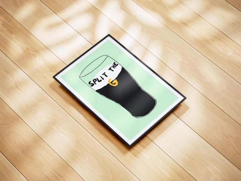 May include: A framed print with a green background and a black and white illustration of a pint glass with the text "Split the G" on the foam.