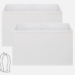 May include: Two rectangular white fabric lamp shades with a clean, structured design. Each shade features a white metal frame visible at the top and includes a separate, detached silver-toned metal harp fitting for lamp assembly.