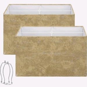 May include: Two rectangular lamp shades with a textured gold finish and white interior lining. The shades feature a structured frame with a white crossbar support. Two separate silver-toned metal harps are included for lamp assembly.