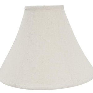 May include: A conical lamp shade with a textured, off-white fabric exterior. The shade features a simple, clean design with a narrow top opening and a wider base, finished with matching fabric trim along the top and bottom edges for a uniform look.
