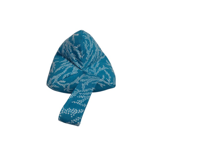 May include: A teal blue meditation cushion with a white floral pattern. The cushion has a handle for easy carrying.