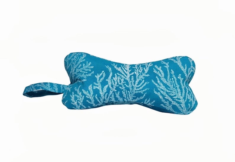 May include: A turquoise blue dog toy shaped like a bone with a white coral pattern.