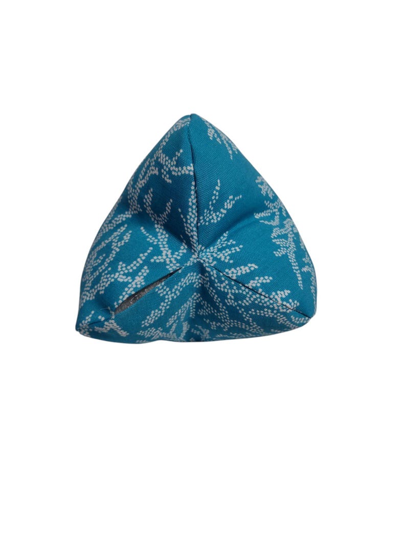 May include: A turquoise blue triangular cushion with a white coral reef pattern.