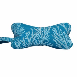 May include: A turquoise blue dog bone shaped cushion with a white coral reef pattern.