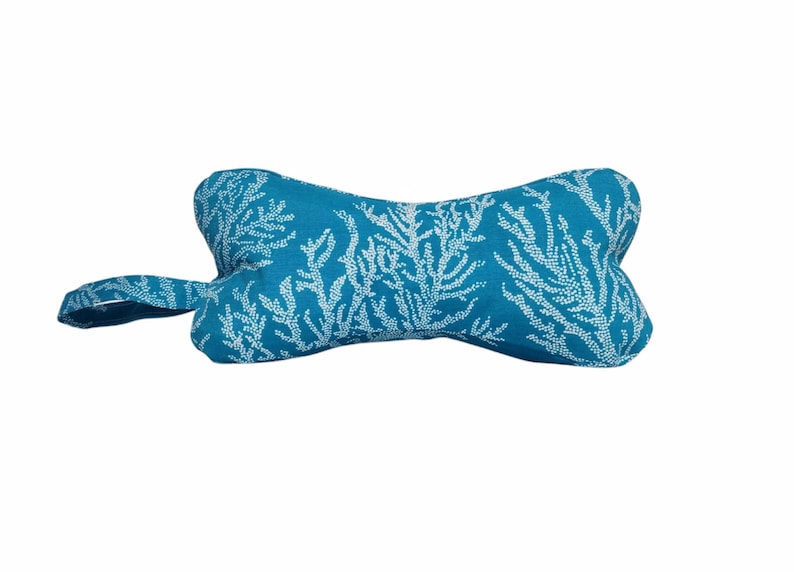 May include: A turquoise blue dog bone shaped cushion with a white coral reef pattern.