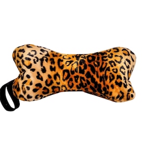 May include: A brown and black leopard print dog bone shaped pillow with a black strap.