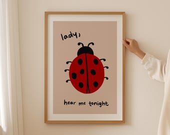 Puede incluir: Lámina enmarcada con un diseño de mariquita de dibujos animados. La mariquita tiene un cuerpo rojo con lunares negros, sobre un fondo beige. Las palabras "lady, hear me tonight" están escritas en letra negra.