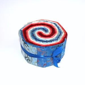 May include: A roll of fabric in shades of blue, red and white, tied with a blue ribbon. The fabric is arranged in a spiral pattern, creating a colourful and eye-catching design.