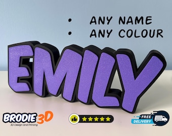 Könnte beinhalten: Ein violettes 3D-Namenschild mit dem Namen "Emily" in einer fetten, Comic-Schriftart. Das Schild besteht aus Schaumstoff und hat einen schwarzen Umriss. Der Text "ANY NAME ANY COLOUR" ist im Hintergrund sichtbar.