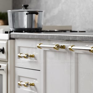 May include: White kitchen cabinets with gold-toned hardware. The cabinets have a sleek, modern design and feature a brushed nickel finish. The hardware is made of a durable metal and is easy to clean.